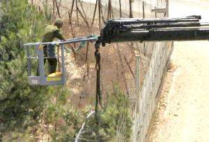 Israeli soldiers use a crane as they cut a tree on the border near the village of Adaisseh
