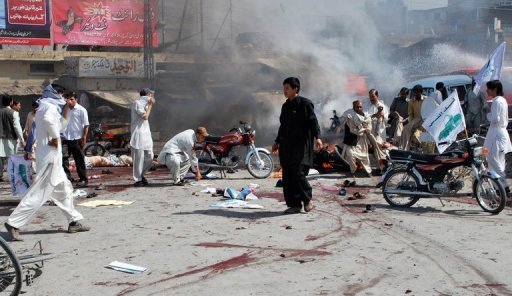 Pakistanis help injured blast victims at the site of a suicide bomb attack
