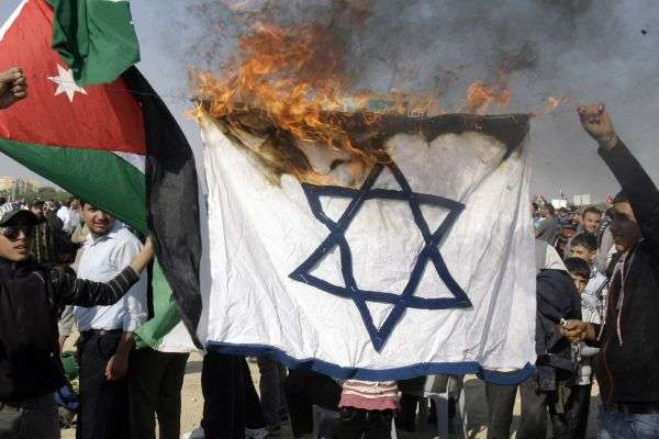Palestinians and Jordanians burn the Israeli flag during a sit-in in Sweimeh to commemorate the 64th anniversary of the partition of Palestine