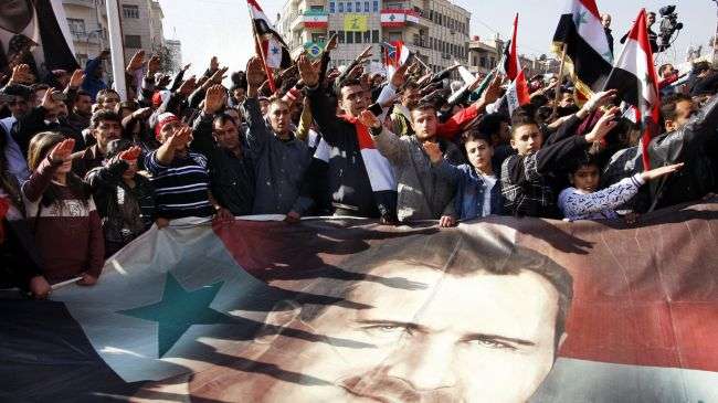 Syrians hold a large poster depicting Syria