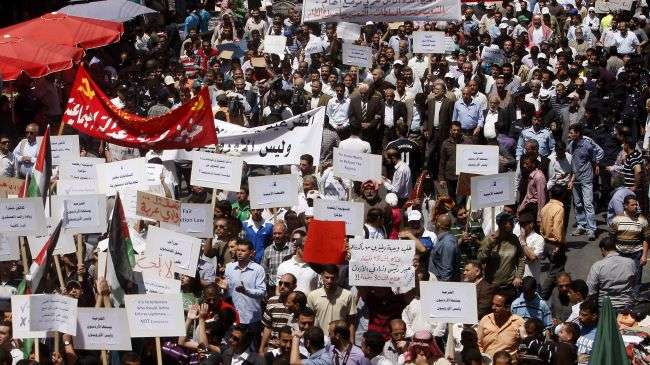 Jordanian protesters hold signs calling for reform as they march during a demonstration in Amman on April 27, 2012.
