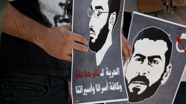 Protesters hold posters depicting Palestinian hunger strikers Thaer Halahla and Bilal Thiab.