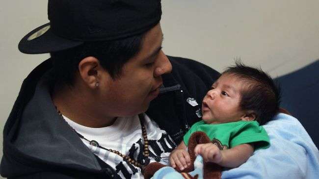 An American citizen holds his six-weeks-old son at a community health center in Aurora, Colorado, March 27, 2012.