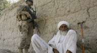 یک سرباز امریکایی در حال آماده باش در کنار یک پیرمرد افغانی در استان هیرمند افغانستان
