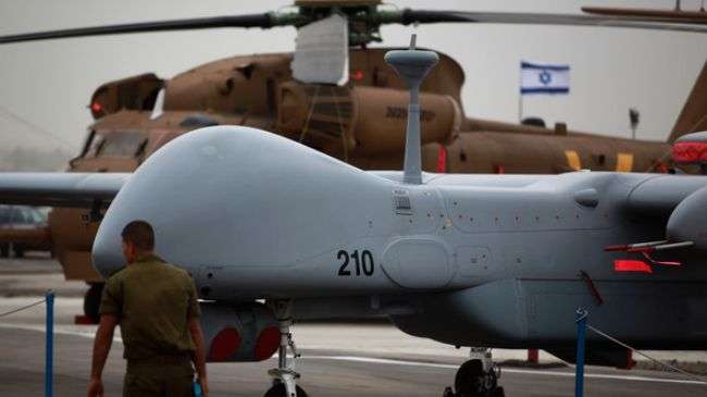 An Israeli soldier stands guard near a drone