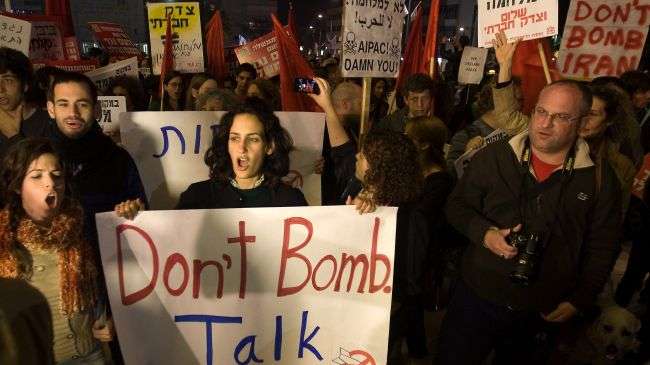 Israeli anti-war protesters march with signs during a demonstration opposing military action against Iran in Tel Aviv on March 24, 2012.