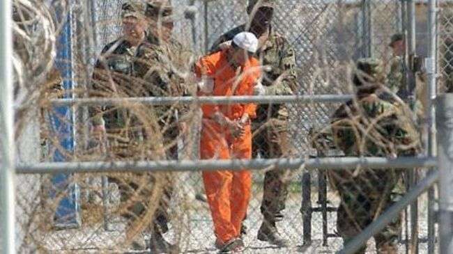 File photo shows a detainee with guards at the US-run prison camp in Guantanamo Bay, Cuba.