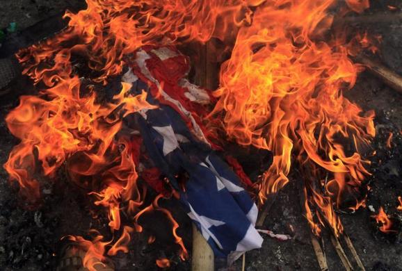 A burning U.S. flag is seen on the ground after it was set on fire by Bangladeshi Muslims during a protest in front of the National Press Club in Dhaka September 21 2012.