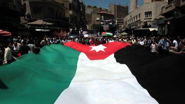 Jordanian protesters hold a giant national flag during a march to protest price hikes in Amman on June 8, 2012.