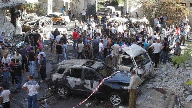Burnt cars are seen after a car bomb exploded at the entrance to a cemetery (in the background) in the Jaramana district of Damascus on August 28, 2012.