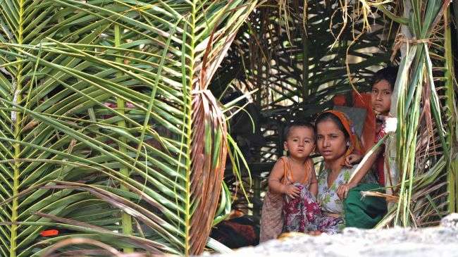 A Muslim Rohingya woman sits with her children in her temporary shelter at a village in Minpyar in Rakhine state on October 28, 2012.