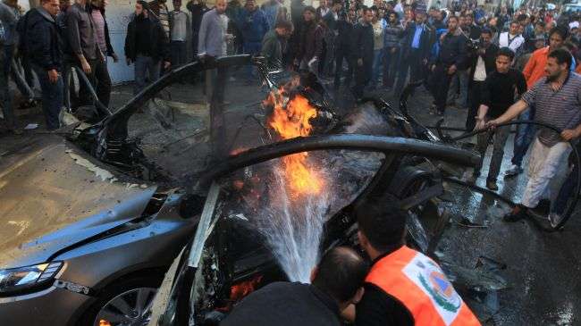 Palestinians extinguish the fire from Ahmad Jabari’s car after it was hit by an Israeli air strike in Gaza City on November 14, 2012.