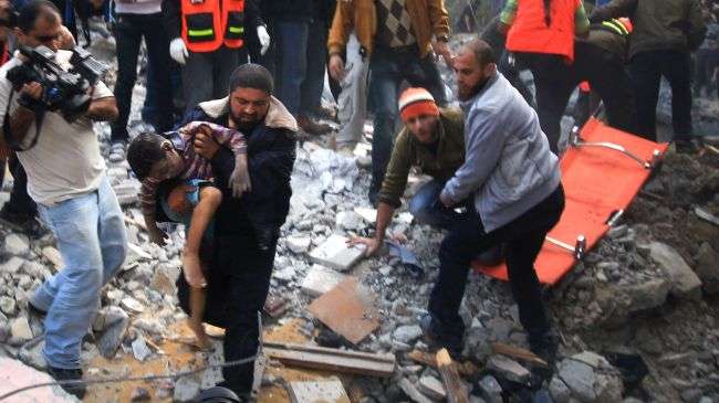 A Palestinian man carries the dead body of a child from the rubble after an Israeli missile struck on a family home in Gaza City on November 18, 2012.