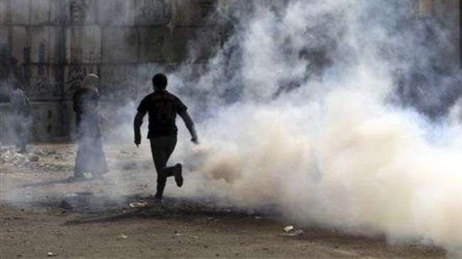 A protester runs with a tear gas canister that was fired by riot police during a demo near the Interior Ministry in Cairo on November 20, 2012.