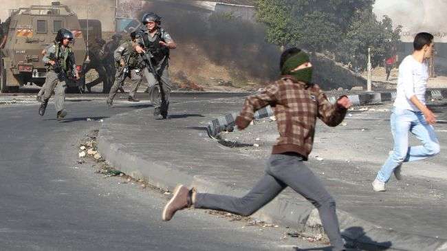 Palestinian protesters are chased by Isareli guards during clashes in the West Bank city of Nablus on November 21, 2012.