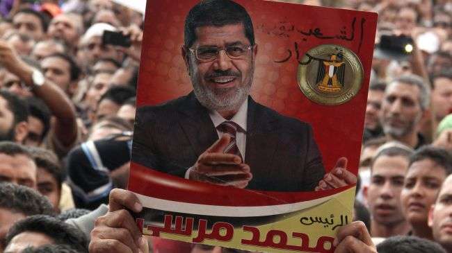 Supporters of Egyptian President Mohamed Morsi hold up a poster of him during a rally outside Cairo’s Presidential Palace on November 23, 2012.