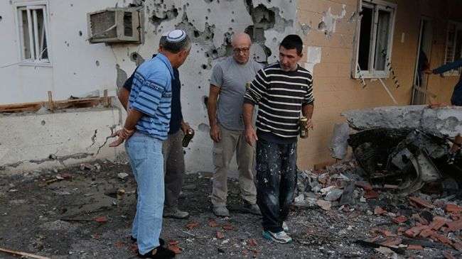 Israeli citizens inspecting the ruins of a house destroyed by Palestinian retaliatory rockets.