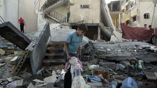 A Palestinian boy holds a doll as he walks amid the rubble of a house destroyed in an Israeli airstrike in Rafah in the southern Gaza Strip on November 20, 2012.