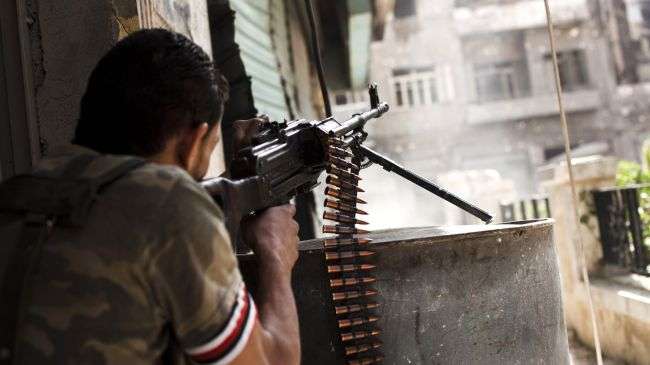 An insurgent in Syria fires his gun at Syrian government troops in Aleppo.