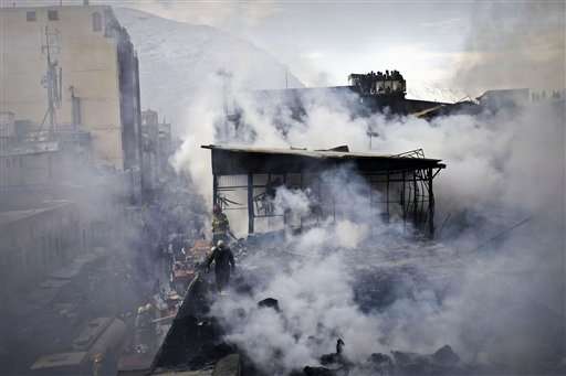 Afghan policemen and fire fighters investigate the scene of a burning market in Kabul, Afghanistan, Sunday, Dec. 23, 2012. Hundreds of shops at a market were burnt in a fire, but no causalities were reported.