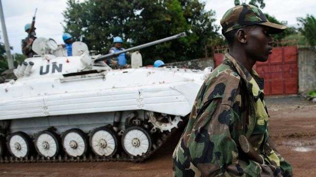 An M23 rebel walks down a street in Goma as an armored personnel carrier of the UN drives past on the edge of Lake Kivu in eastern Democratic Republic of Congo on November 20, 2012.