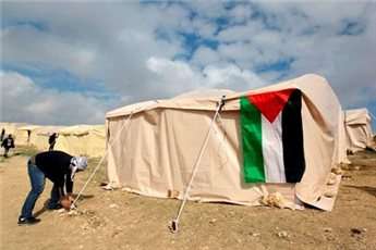 A flag hangs on a newly-erected tent as a Palestinian activist secures a rope, in an area known as E1, near Jerusalem January 11, 2013.