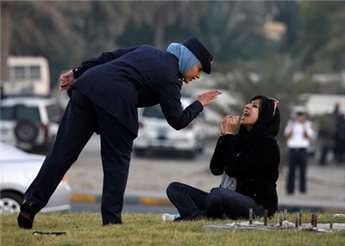 A police officer speaks to Zaynab al-Khawaja, the daughter of human rights activist, Abdulhadi al-Khawaja, after she refused to leave after a sit-in at a roundabout west of Manama.
