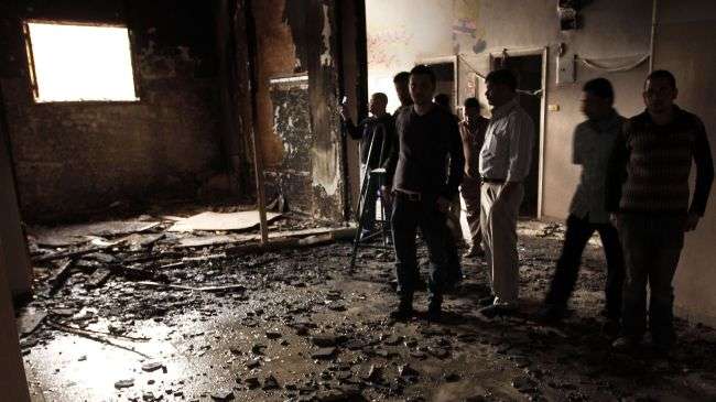 People inspect a destroyed room in a building which was burnt down during clashes between Christians and Muslims in al-Khusus town, Egypt, on April 6, 2013.