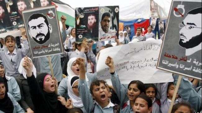 File photo shows Palestinian protesters carrying pictures of Thaer Halahla and Bilal Diab who were on a hunger strike in an Israeli jail in 2012.
