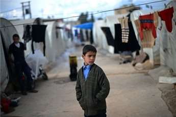 An internally displaced Syrian boy stands in a camp along the Turkish border in Aleppo province.