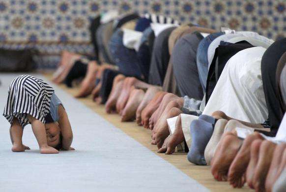A child is seen near members of the Muslim community attending midday prayers at Strasbourg Grand Mosque in Strasbourg on the first day of Ramadan July 9 2013.