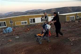 Israeli settlers walk through the makeshift outpost of Nofi Nehemya.