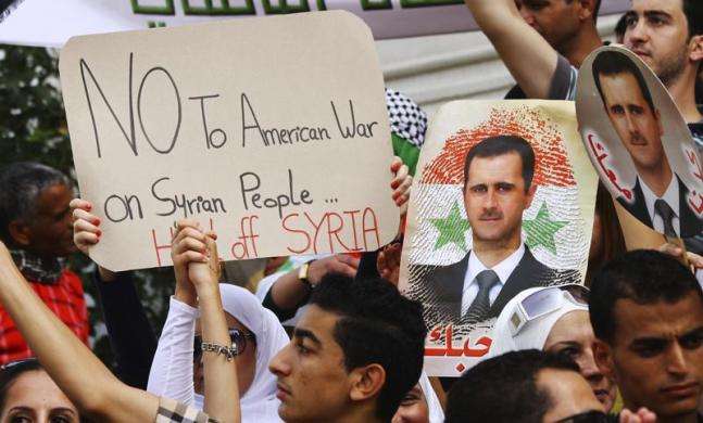 Protesters hold signs and images of Syrian President Bashar al-Assad during a demonstration against the possibility of a U.S. military strike against the Syrian government in Tunis August 30 2013.
