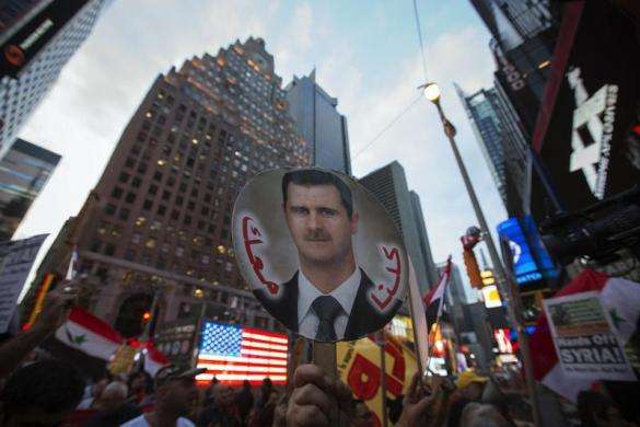 Local activists and Syrian-American supporters of Syrian President Bashar al-Assad hold up his image during an anti-war rally in front of a U.S. Armed Forces Recruiting Station in Times Square August 29 2013.