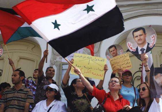Protesters shout slogans as they wave a Syrian flag and hold images of Syrian President Bashar al-Assad during a demonstration against the possibility of a U.S. military strike against the Syrian government in Tunis August 30 2013.
