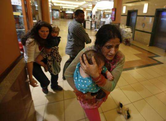 Women carrying children run for safety as armed police hunt gunmen who went on a shooting spree in Westgate shopping centre in Nairobi September 21 2013.