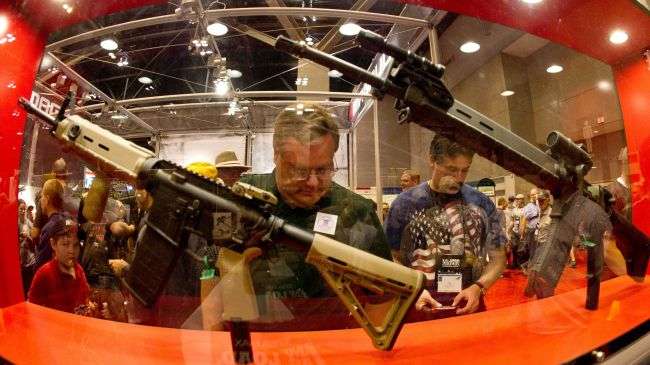Gun enthusiasts look at various firearms on the floor at the National Rifle Association (NRA) Annual Meetings and Exhibits in this April 14, 2012 file photo in St. Louis, Missouri.