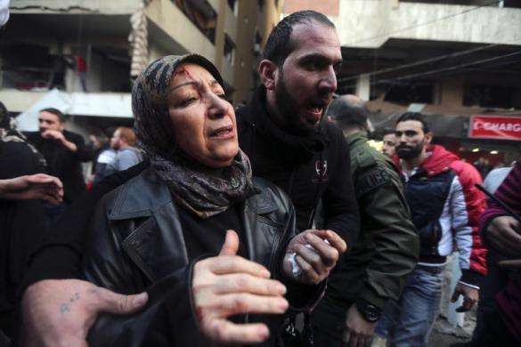 A wounded woman reacts as she is helped by a man at the site of an explosion in Beirut southern suburbs January 2 2014.
