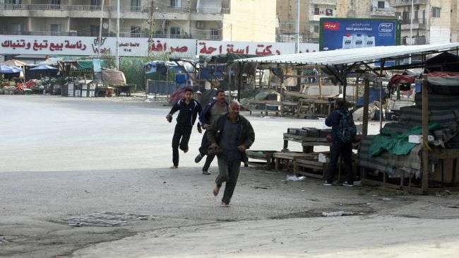 People run for cover from sniper fire during clashes between supporters and opponents of Syrian government in the Lebanese city of Tripoli on December 1, 2013.