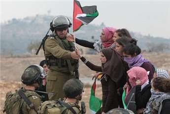 An Israeli soldier gestures to female protesters to move away during a demonstration against the building of a nearby Jewish settlement in the occupied West Bank on Dec. 7, 2013