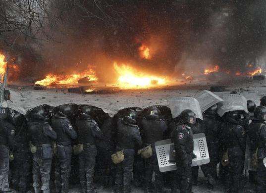 Interior Ministry members stand in formation in front of burning tires set ablaze by pro-European protesters during clashes in Kiev January 22 2014.