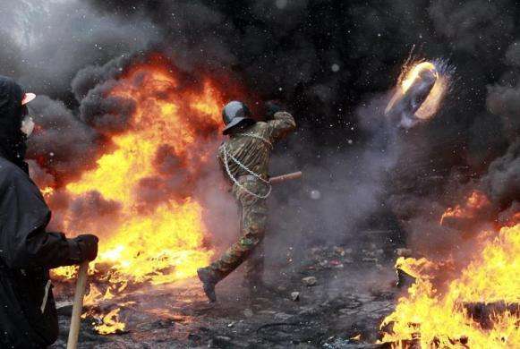 A pro-European protester throws a burning tyre during clashes with riot policemen in Kiev January 22 2014.