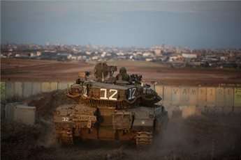A picture taken from Israel shows an Israeli Merkava tank taking position along the southern border with the Gaza Strip (Back) on Dec. 25, 2013