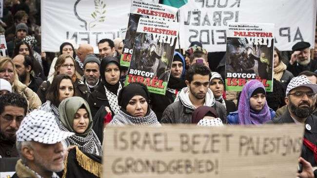 Demonstrators hold signs reading, No Dutch support for apartheid in Palestine, Boycott Israel, during a protest in Amsterdam.