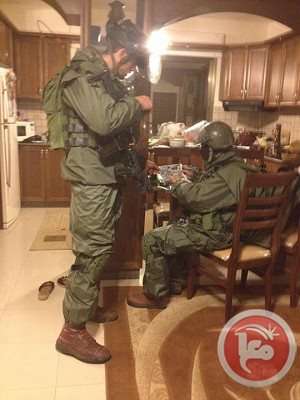 Soldiers inspect a camp resident kitchen during a raid