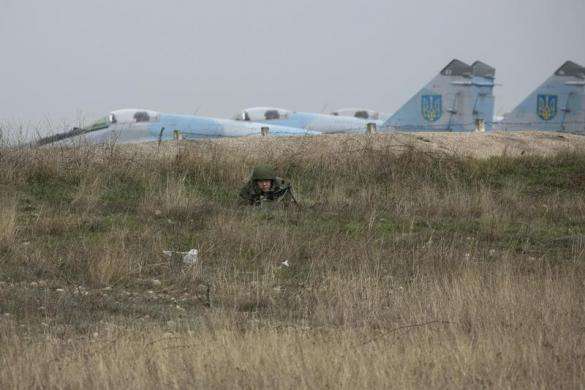 A Russian soldier lies with his back to Ukrainian fighter jets he watches Ukrainian serviceman at the Belbek airport in the Crimea region March 4 2014.