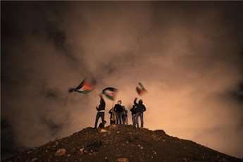Palestinians wave the national flag as they await the release of prisoners in Jerusalem on December 31, 2013.