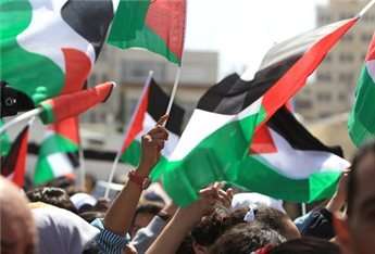 Palestinians wave their national flag on March 20, 2014, in the West Bank city of Ramallah