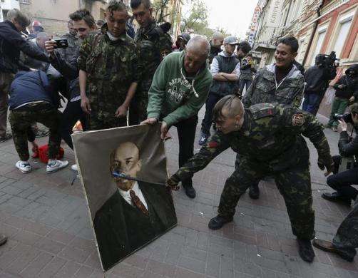 A member of the Maidan self-defense forces damages a portrait of Soviet state founder Vladimir Lenin taken from the Ukrainian Communist party headquarters in Kiev April 9 2014.