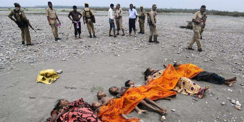 Polisi India berdiri di dekat jasad anak-anak dan perempuan yang ditemukan di Sungai Beki di dekat desa Khagrabari, sekitar 200 kilometer dari ibu kota negara bagian Assam, Guwahati. Mereka adalah sebagian korban tewas penyerangan brutal yang terjadi di Assam (Kompas)